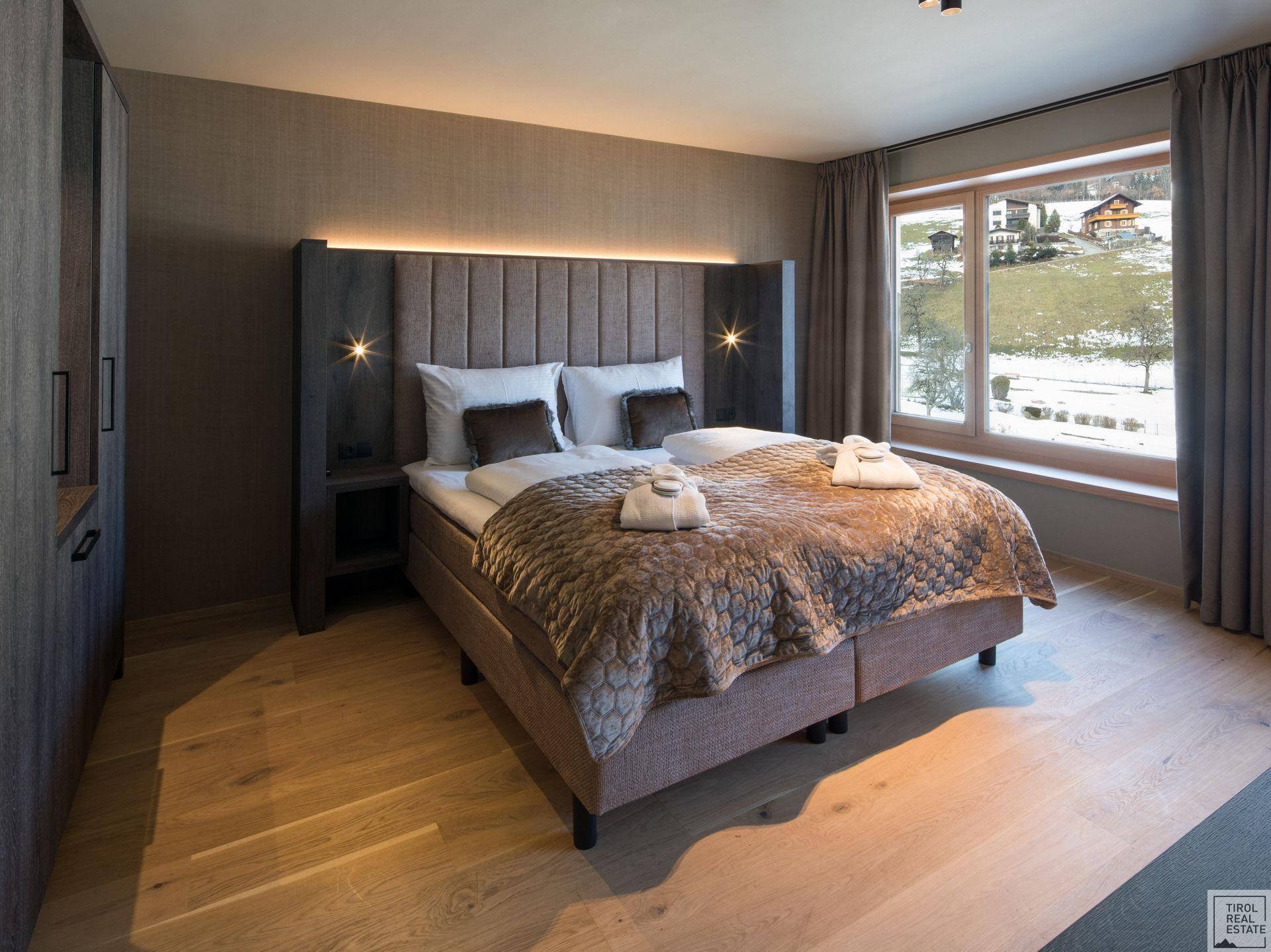 Gemütliches Schlafzimmer mit großem Fenster und Blick auf die verschneite Landschaft.