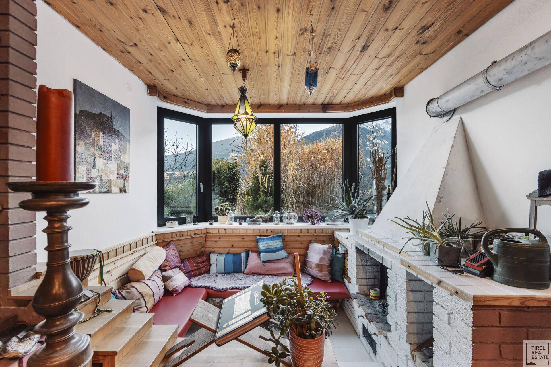 Gemütlicher Wintergarten mit Holzbalkendecke, Sitzbank und Kamin.