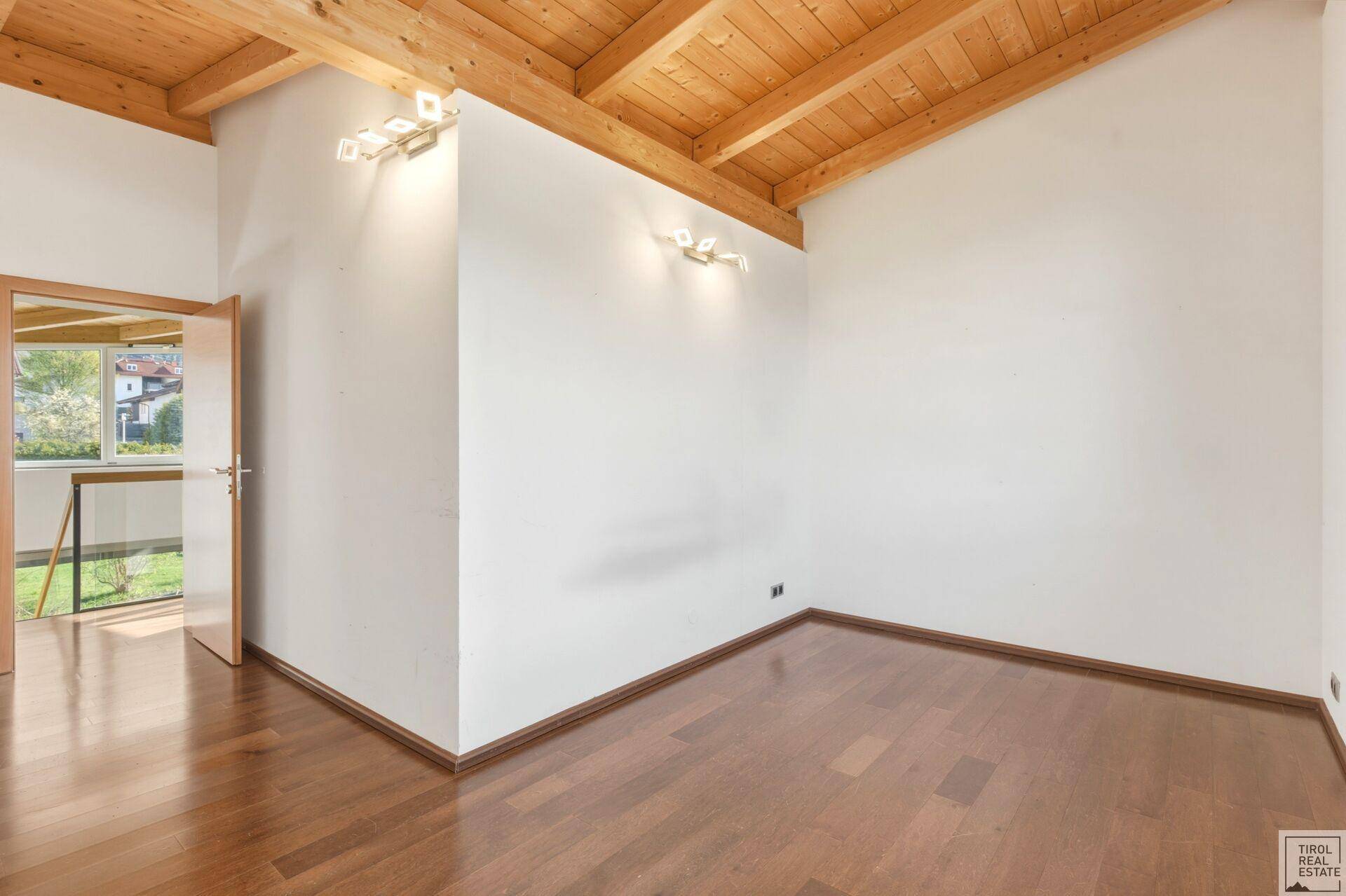 Helles Schlafzimmer mit Holzboden und Holzbalkendecke, bereit zur individuellen Gestaltung.