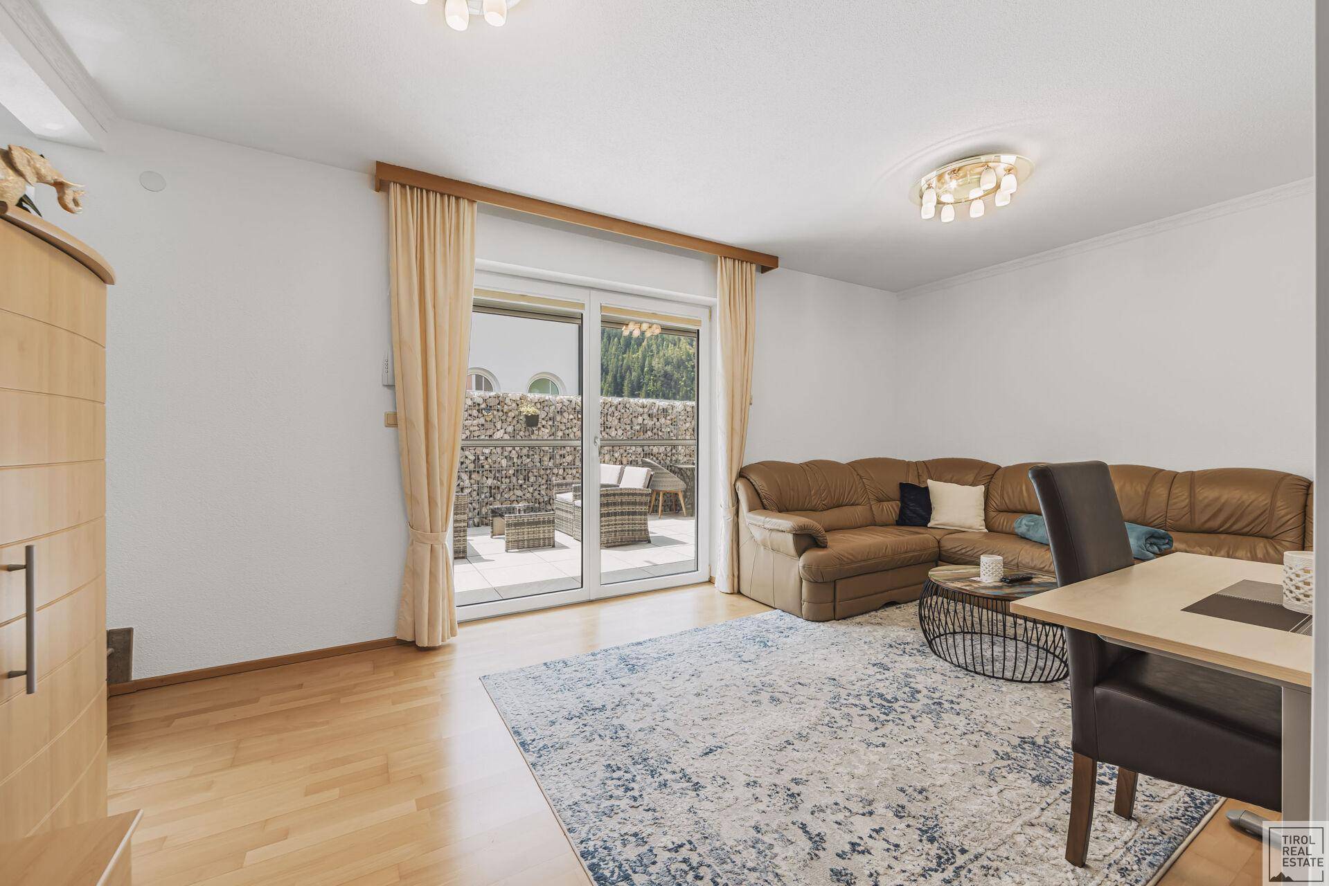 Wohnzimmer mit Holzboden, bequemer Couch und Zugang zur Terrasse.