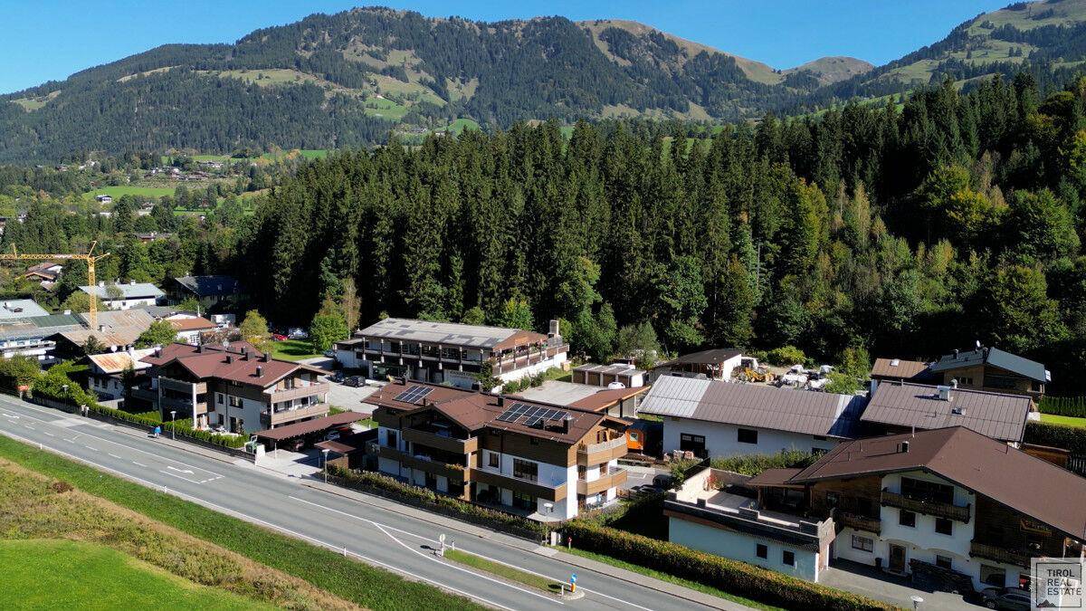 Luftaufnahme eines Dorfes in den Bergen mit Wohnhäusern und umliegender Natur.