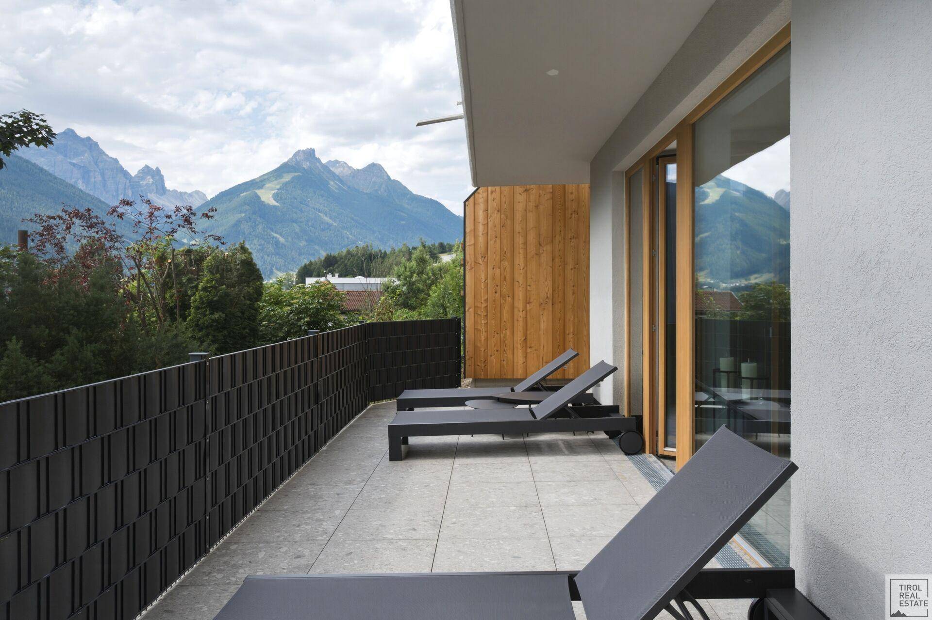 Großer Balkon mit bequemen Liegestühlen und atemberaubendem Blick auf die umliegende Bergwelt.