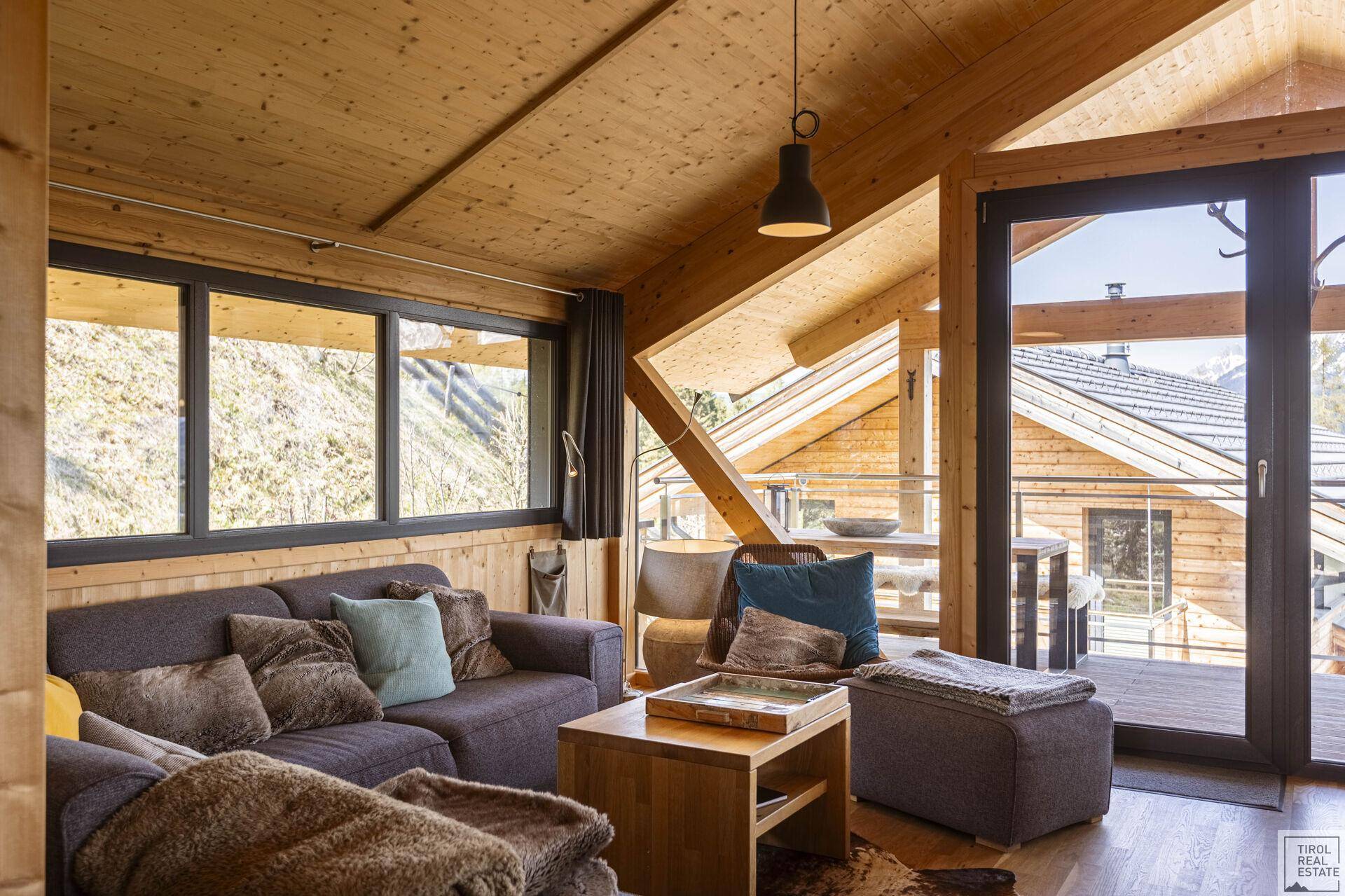 Heller Wohnbereich mit bequemer Sitzecke, Holzwänden und Zugang zum Balkon.