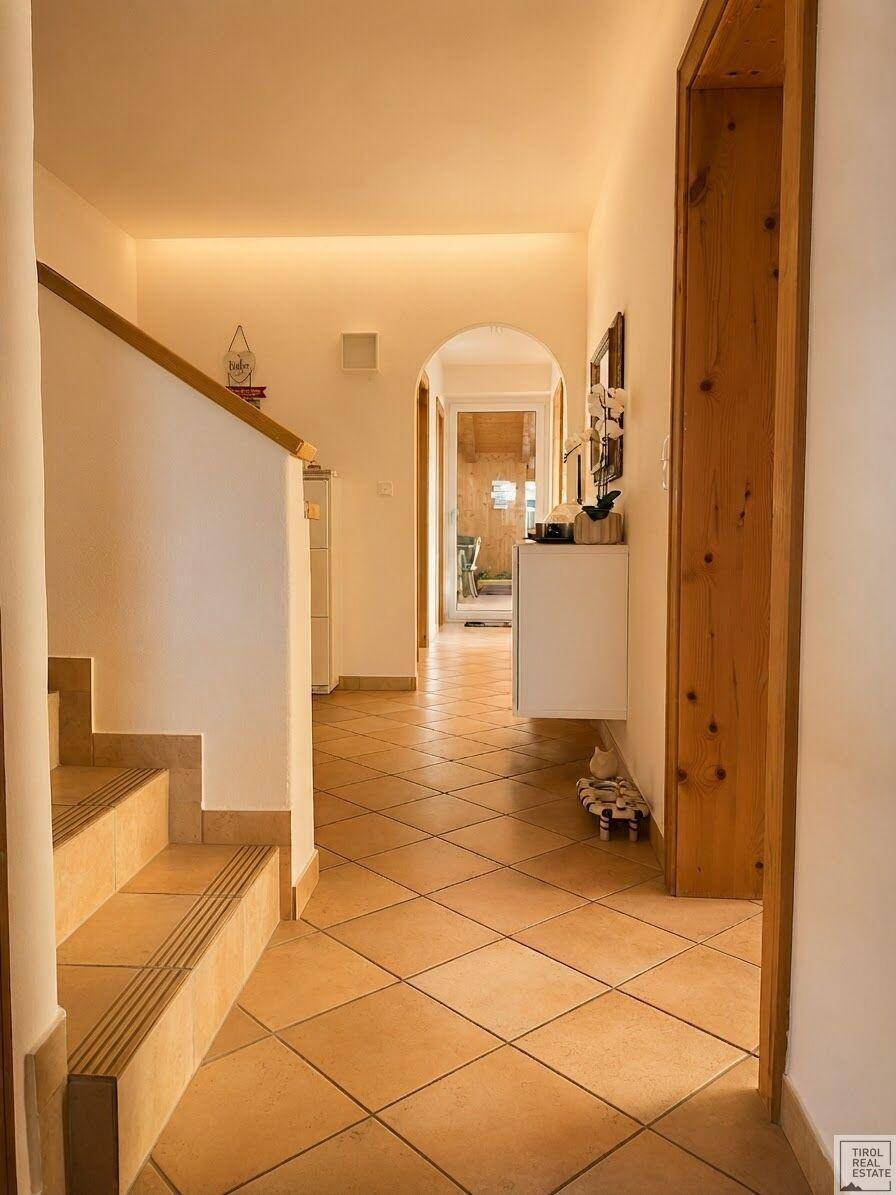 Geräumiger Flur mit Fliesenboden, Treppe und einem Bogendurchgang, der zu weiteren Räumen führt.