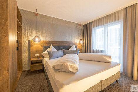 Gemütliches Schlafzimmer mit Doppelbett, Teppichboden und großem Fenster für viel Tageslicht.