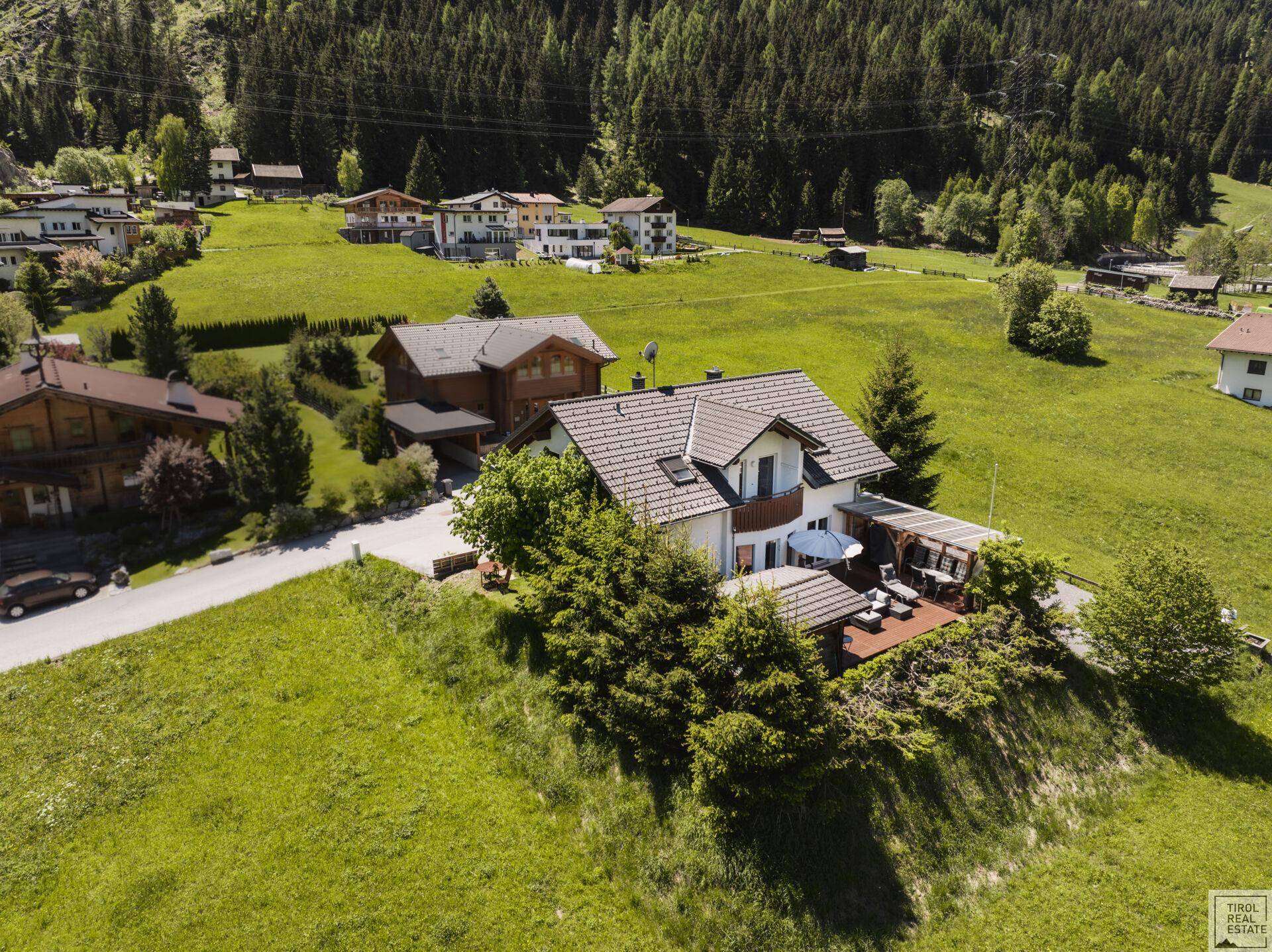 Vogelperspektive eines charmanten Hauses mit Satteldach, umgeben von grünen Wiesen und Bäumen.