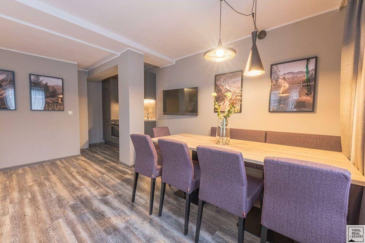 Einladender Essbereich mit langem Holztisch und lila Stühlen, verbunden mit der Küchenzeile.