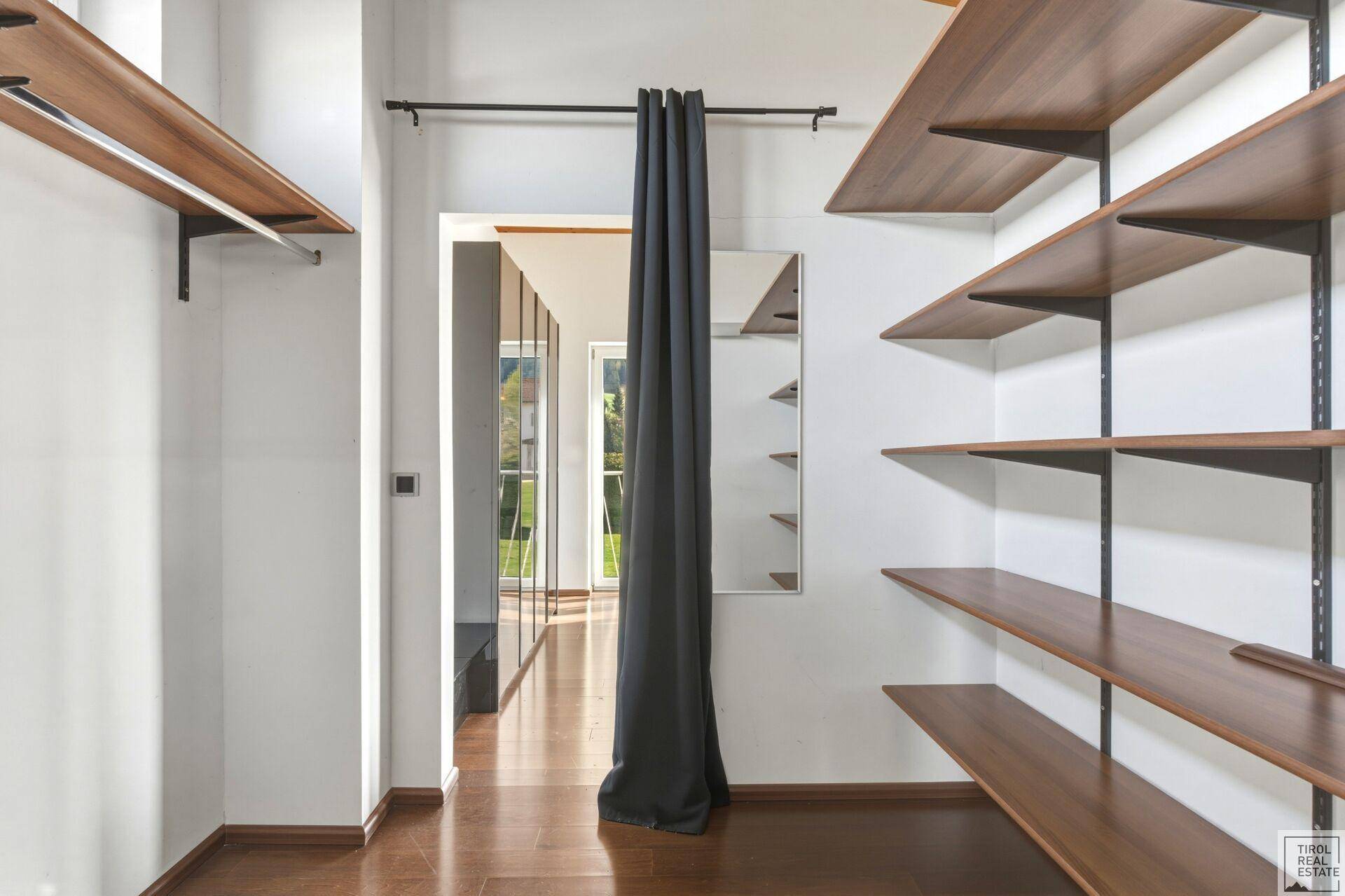 Praktischer begehbarer Kleiderschrank mit offenen Regalen und viel Stauraum für Kleidung.