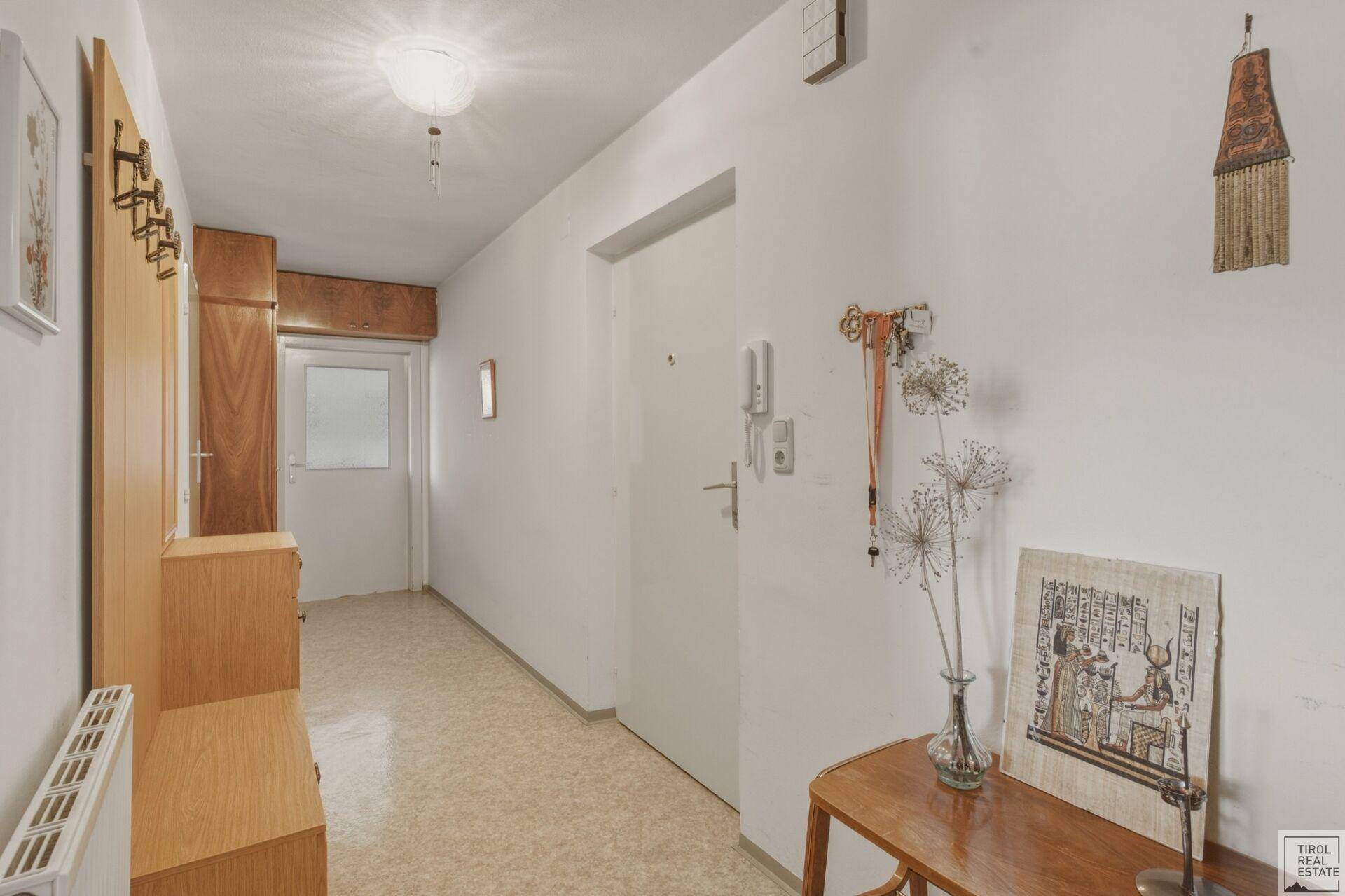 Eingangsbereich mit heller Fliesenboden und praktischer Garderobe, die zum Wohnbereich führt.