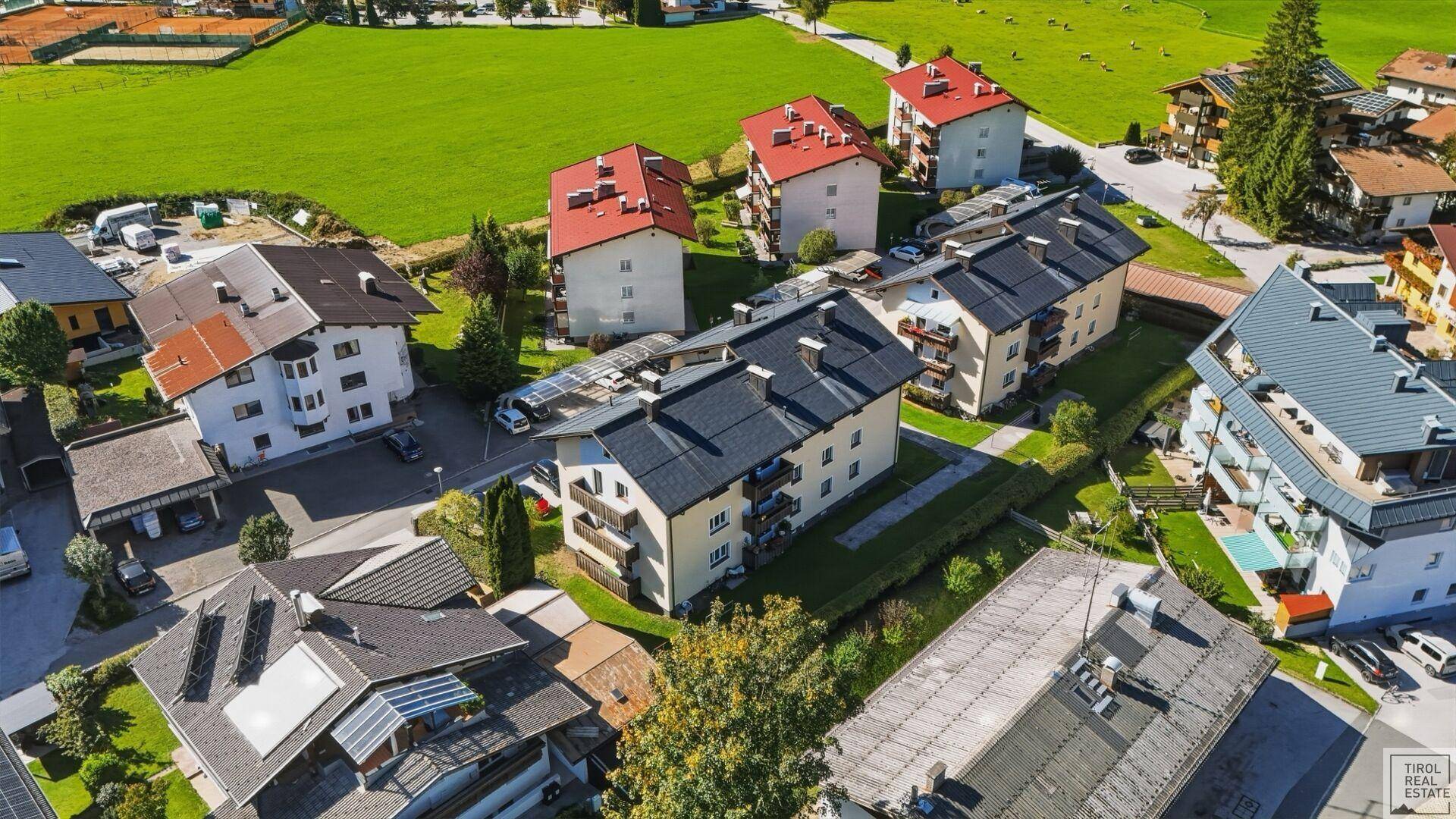 Weitläufige Luftaufnahme der Wohnsiedlung eingebettet in eine grüne Berglandschaft.