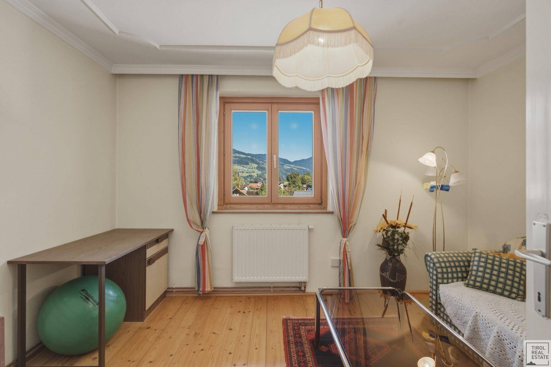 Wohnzimmer mit Holzboden, Sofa und Fenster mit weitem Blick auf die Landschaft.