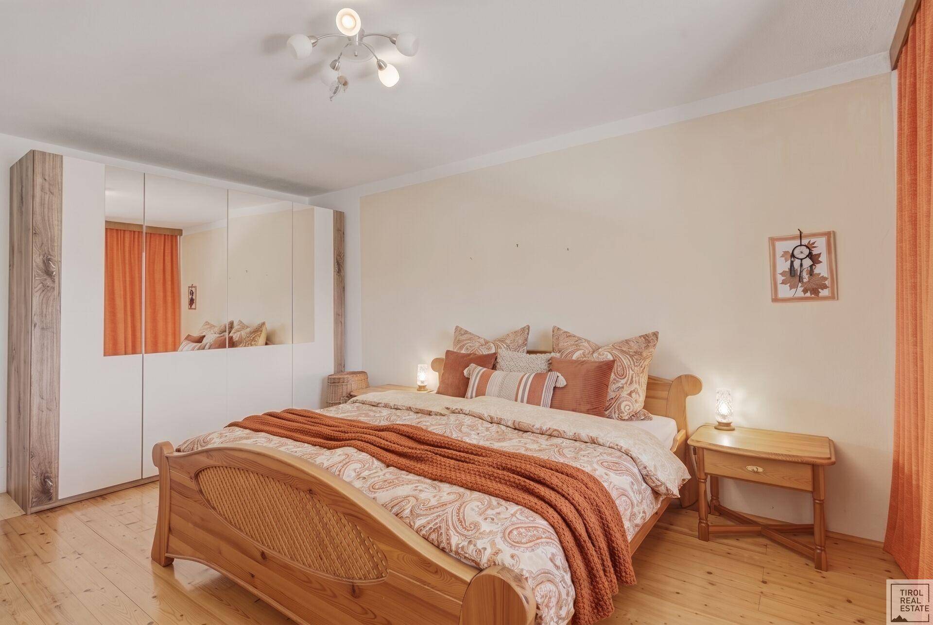 Geräumiges Schlafzimmer mit Holzboden, großem Bett und Spiegelschränken.