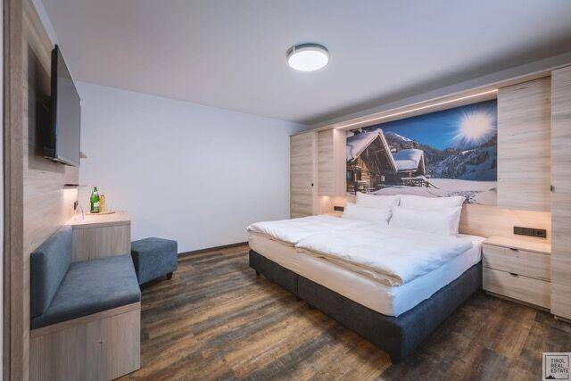 Modern eingerichtetes Schlafzimmer mit Doppelbett, Holzboden und Wandbild mit Winterlandschaft.