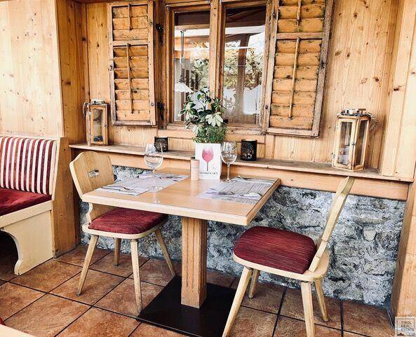 Rustikaler Essbereich mit Holztisch, Stühlen und Fenster mit traditionellen Holzläden.