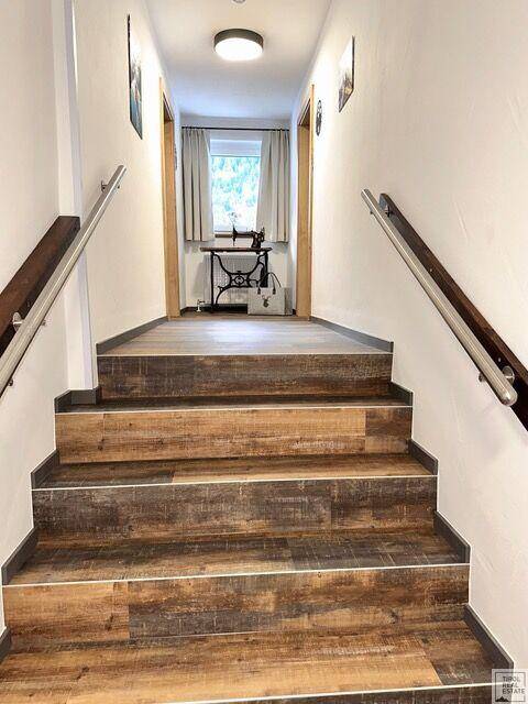 Treppenhaus mit Holzstufen und Handläufen, das zu einem oberen Stockwerk führt.