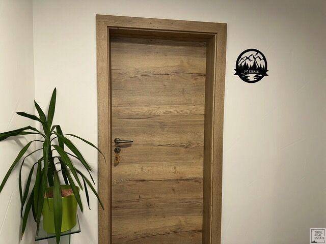 Holztür in einem hellen Flur mit einer Pflanze und Wanddekoration.