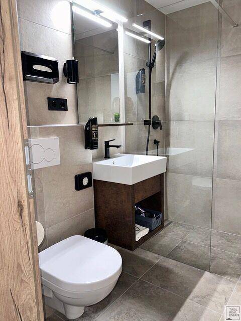 Modernes Badezimmer mit Waschtisch, Toilette und Duschkabine mit Glaswand.