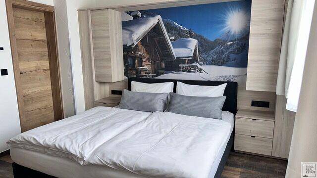 Schlafzimmer mit Doppelbett, Holzboden und Wandbild mit Winterlandschaft.