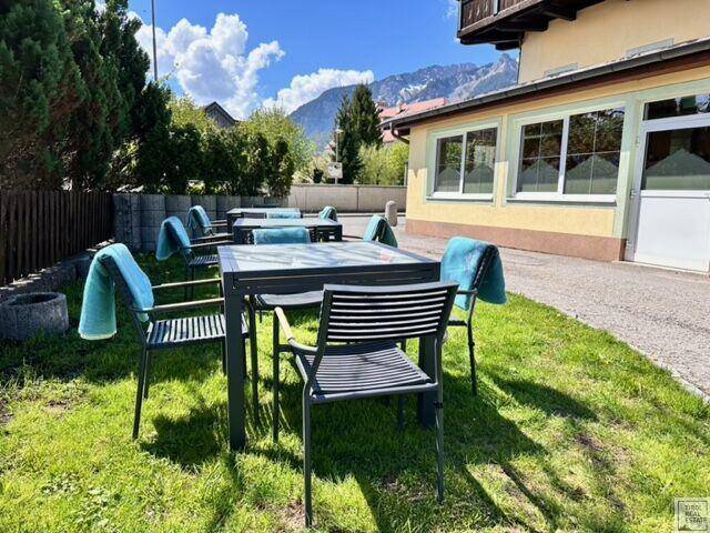 Gepflegter Gartenbereich mit Tischen und Stühlen, ideal für entspannte Stunden im Freien mit Bergblick.