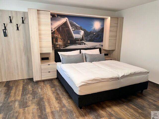 Schlafzimmer mit Doppelbett, Holzboden und integrierten Schränken, dekoriert mit Wintermotiv.