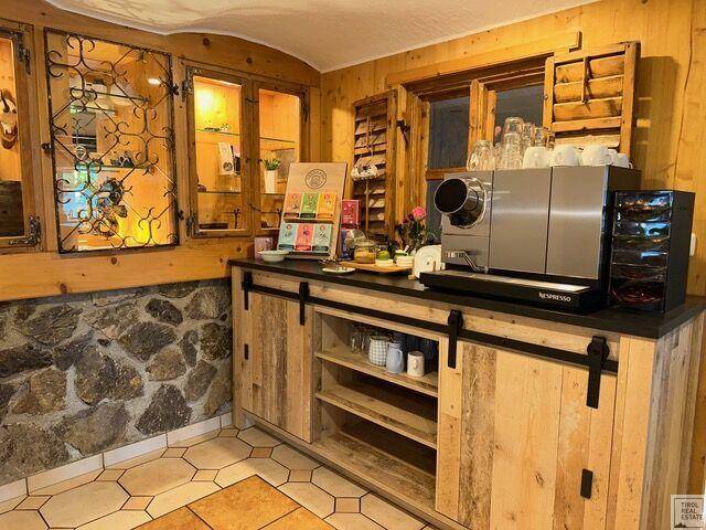Kleine Küchenzeile mit Kaffeemaschine, Holzschränken und einer rustikalen Steinwand.