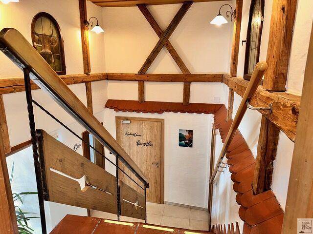 Traditionelles Treppenhaus mit Holzbalken, Geländer und dekorativen Elementen.