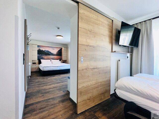 Gemütliches Schlafzimmer mit Holzboden, Schiebetür und einem großen Bett mit Wandbild.