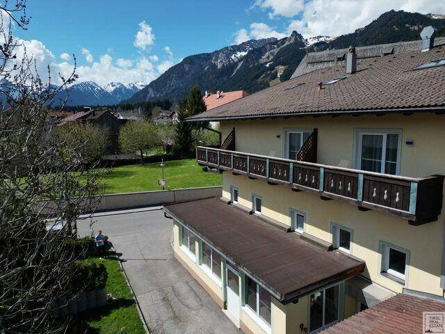 Panoramablick auf das Gebäude mit seinen Balkonen, umgeben von Natur und majestätischen Bergen.