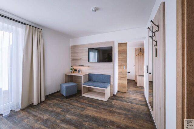 Helles Schlafzimmer mit Holzboden, Schreibtisch und Zugang zu einem Balkon.