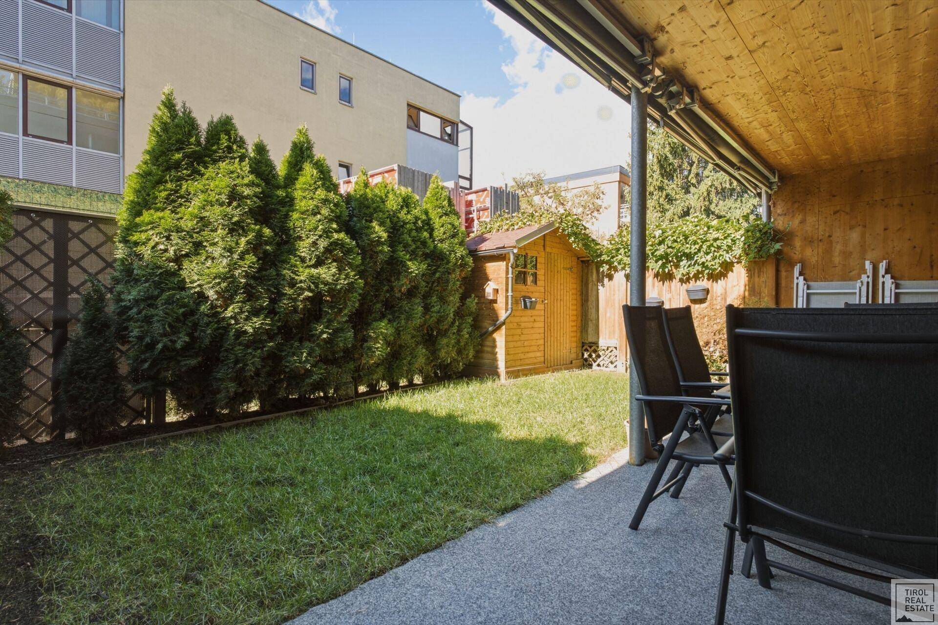 Gepflegter Gartenbereich mit Rasenfläche, Gartenhaus und Sitzgelegenheiten im Freien.