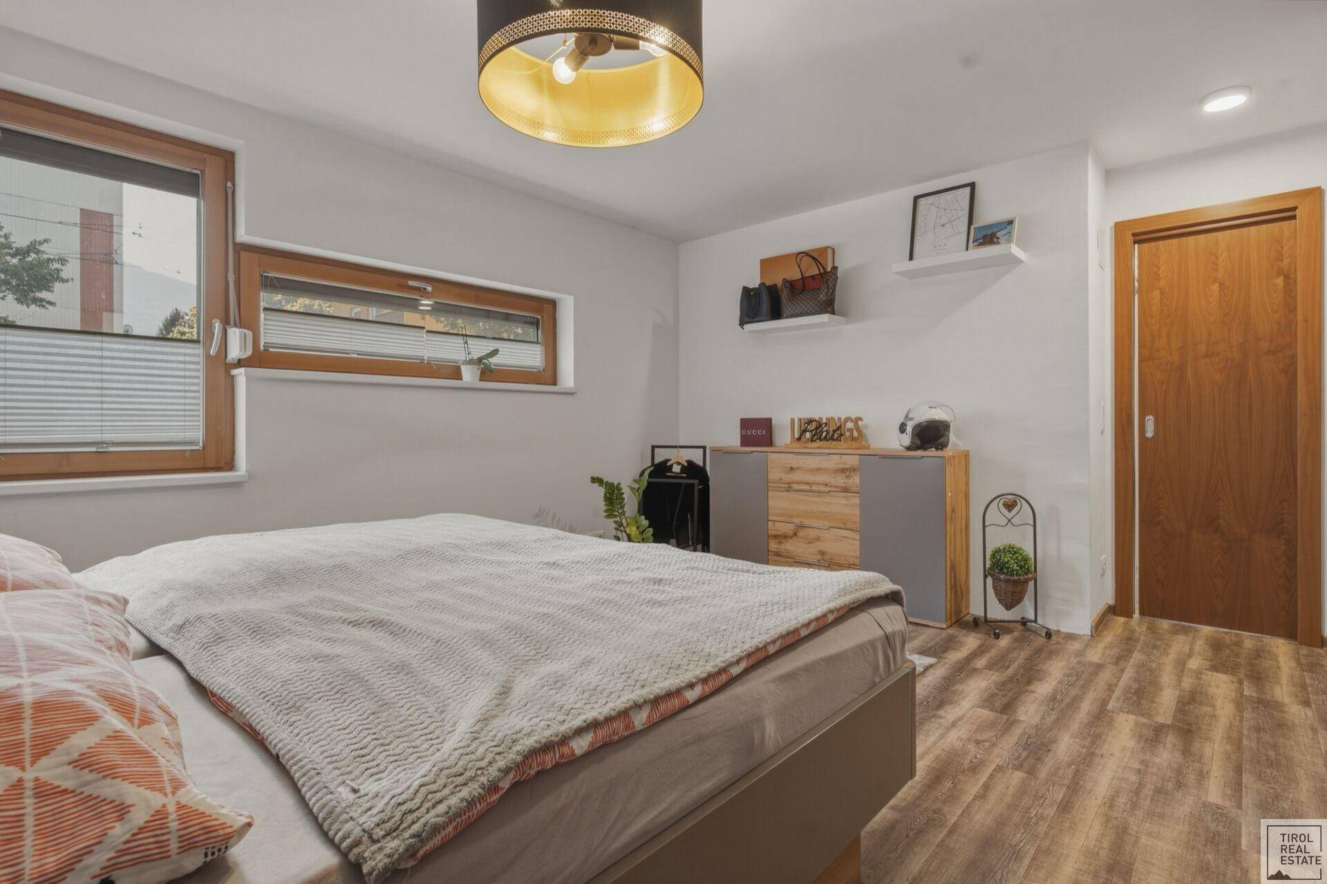 Helles Schlafzimmer mit Doppelbett, Holzboden und Fenster für natürliche Belichtung.