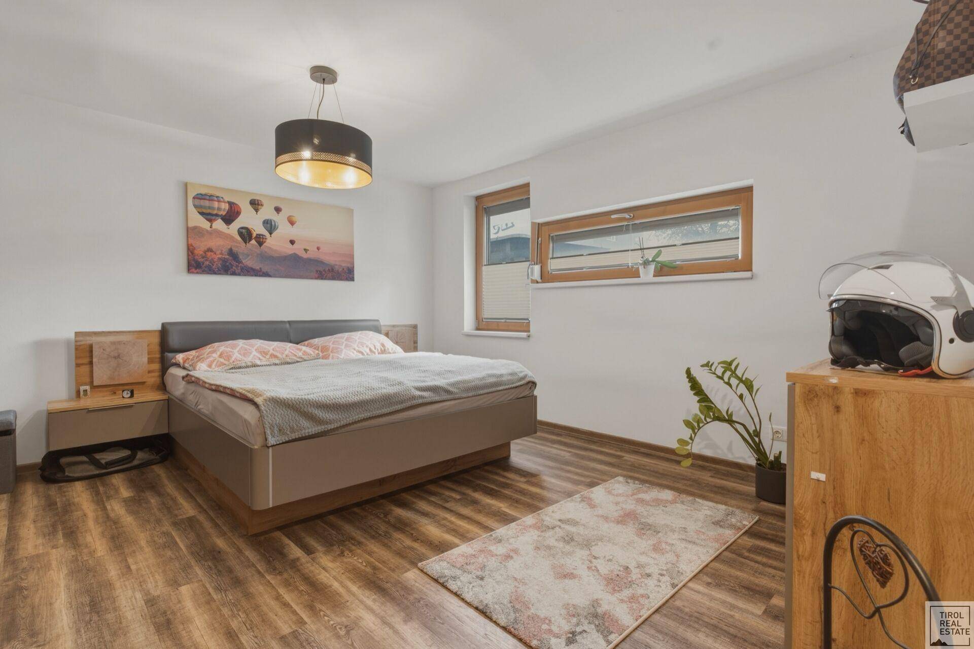 Gemütliches Schlafzimmer mit modernem Bett, Holzboden und einem Fenster.