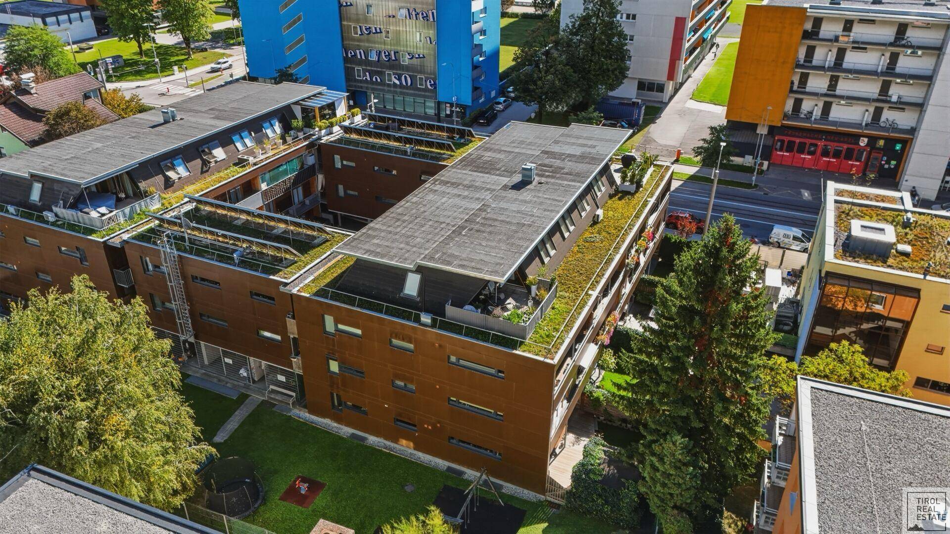 Luftaufnahme eines modernen Wohnkomplexes mit begrünten Dächern und Innenhof.
