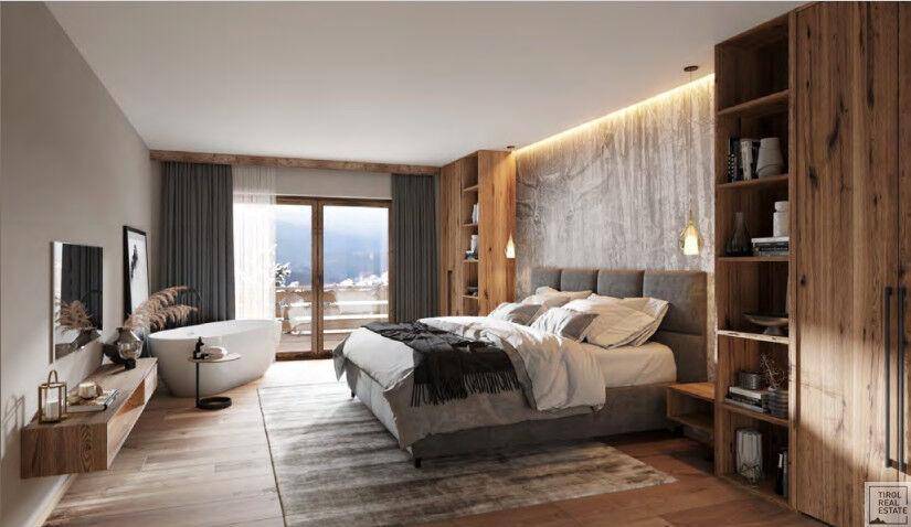 Gemütliches Schlafzimmer mit Holzboden, großem Bett und freistehender Badewanne mit Bergblick.