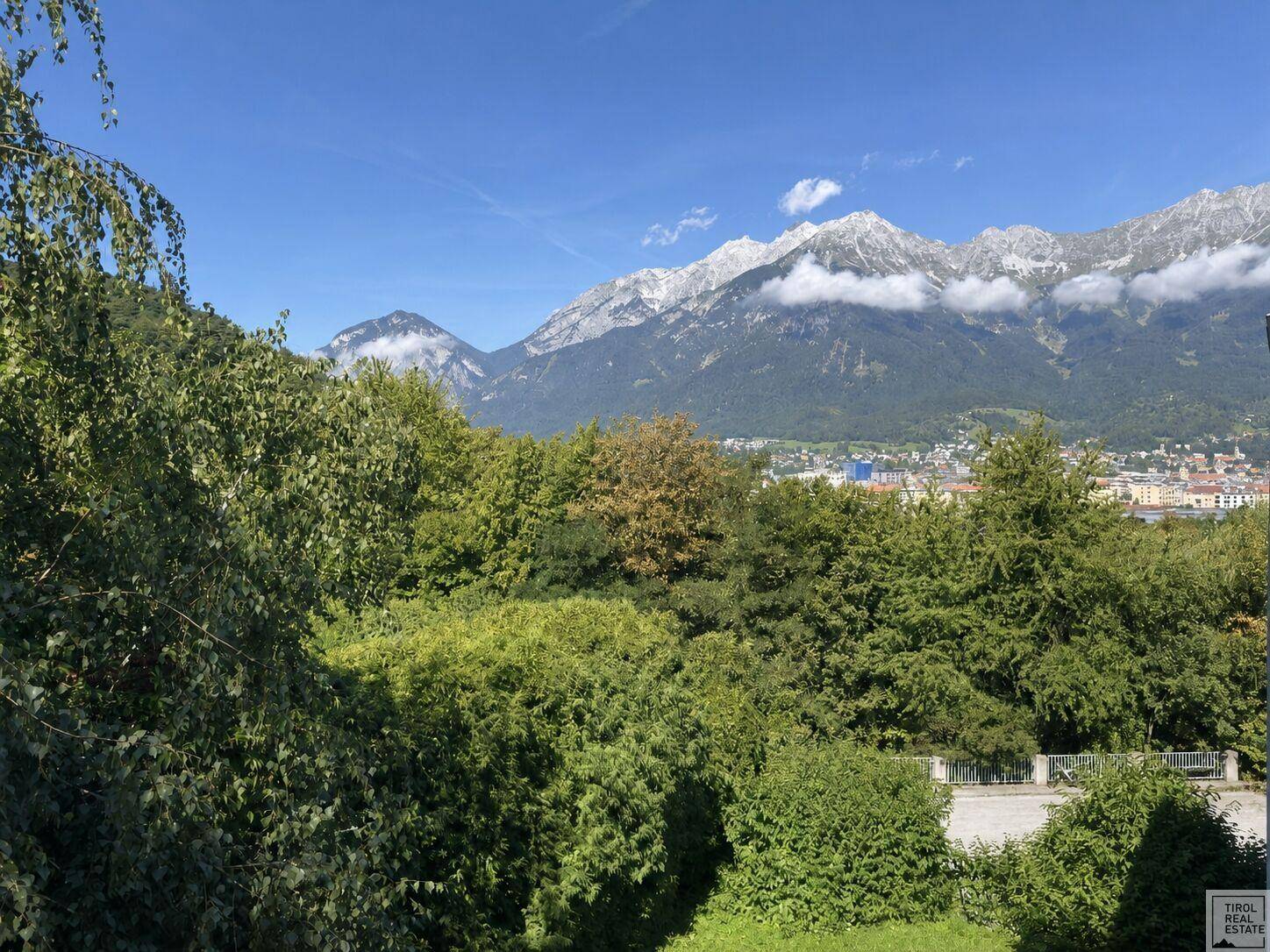 Weitläufiger Panoramablick auf majestätische Berge, üppige Bäume und eine Stadt in der Ferne.