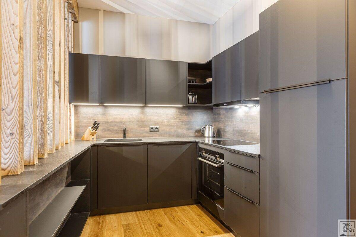 Moderne Küche mit grauen Schränken, integrierten Geräten und Holzboden.
