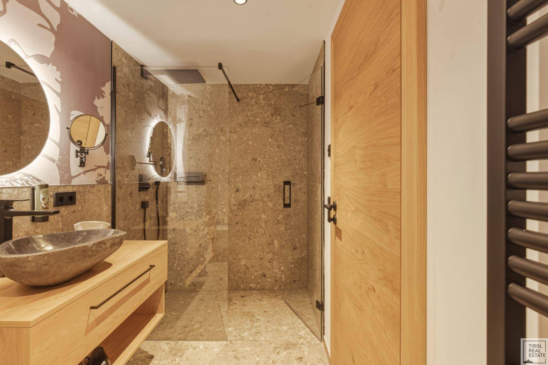 Modernes Badezimmer mit begehbarer Dusche, Natursteinfliesen und einem Holzwaschtisch.