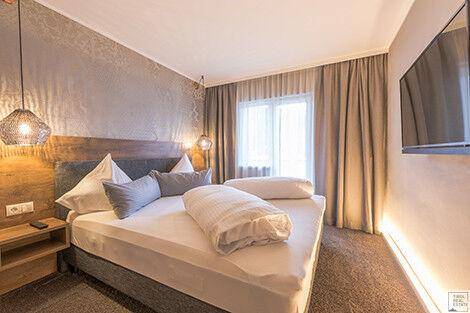 Helles Schlafzimmer mit modernem Design, bequemen Bett und Wandfernseher.