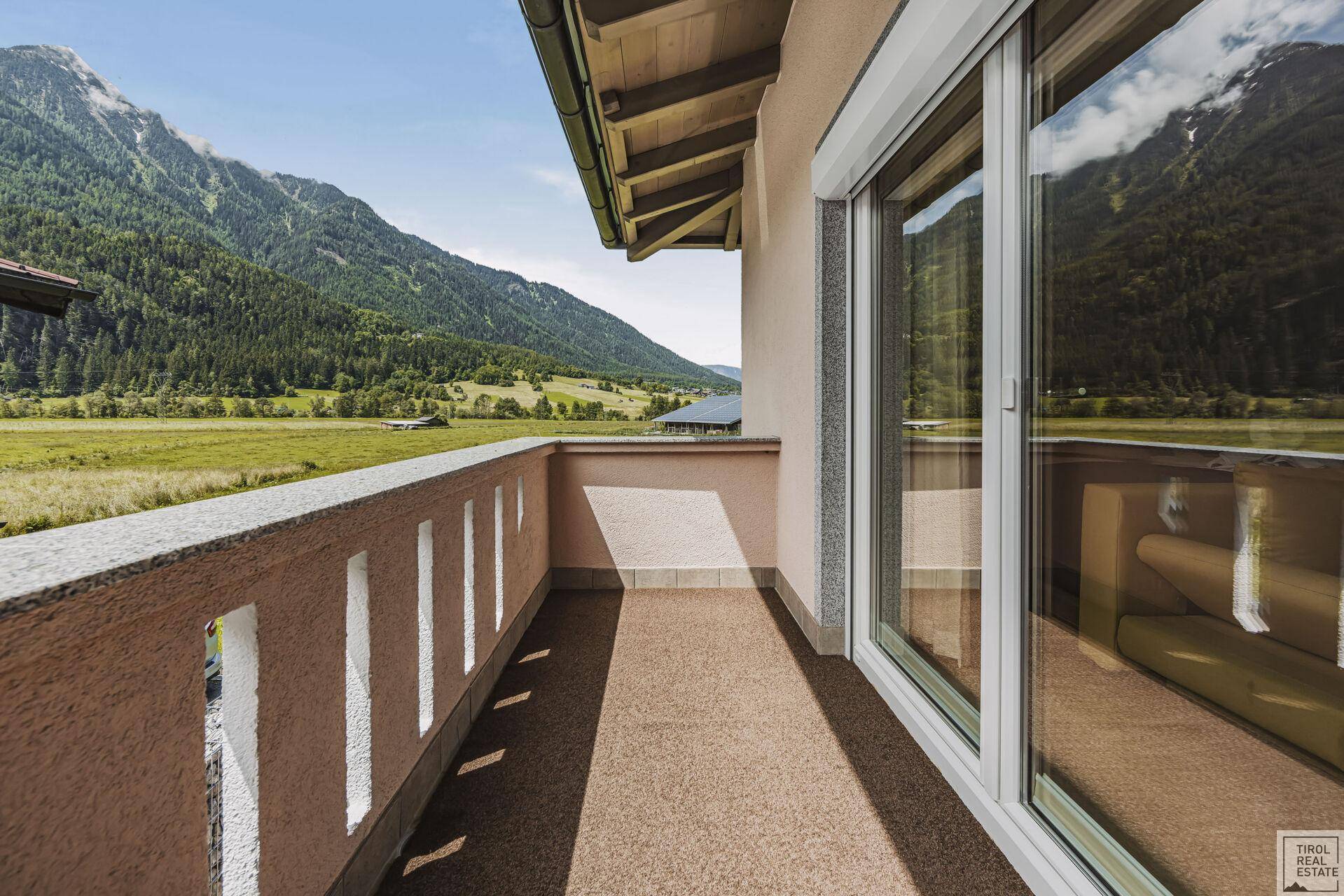 Balkon mit schöner Aussicht auf die grüne Landschaft und die Berge.