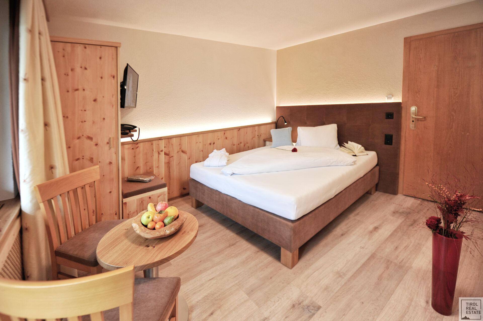 Schlafzimmer mit Einzelbett, Holzelementen, kleinem Tisch und einem Schrank an der Wand.