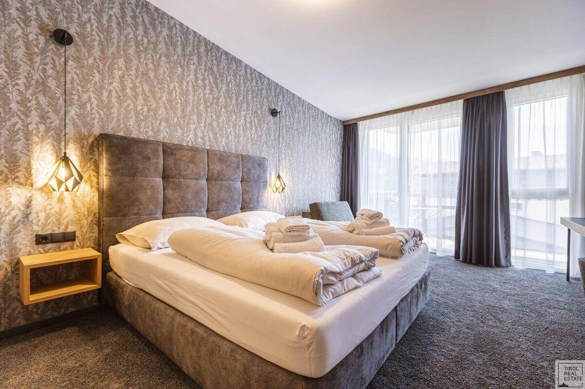 Komfortables Schlafzimmer mit großem Doppelbett, Teppichboden und Zugang zum Balkon.