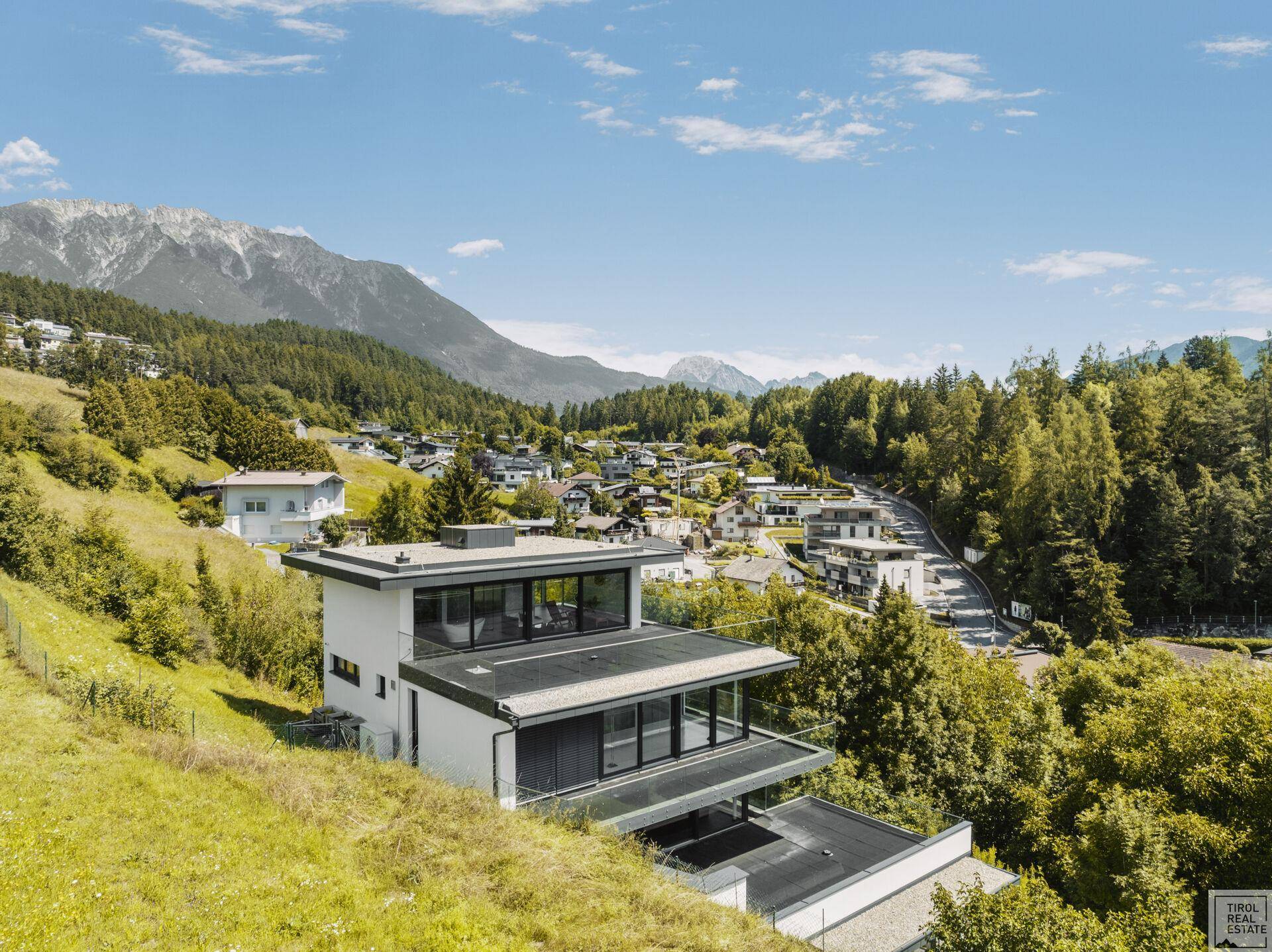 Panoramablick auf die moderne Villa und die umliegende Siedlung in der alpinen Region.
