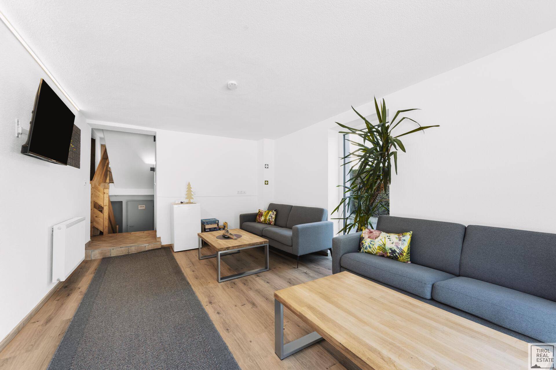 Gemütliches Wohnzimmer mit Holzboden, modernen Möbeln und Blick auf den Treppenaufgang.