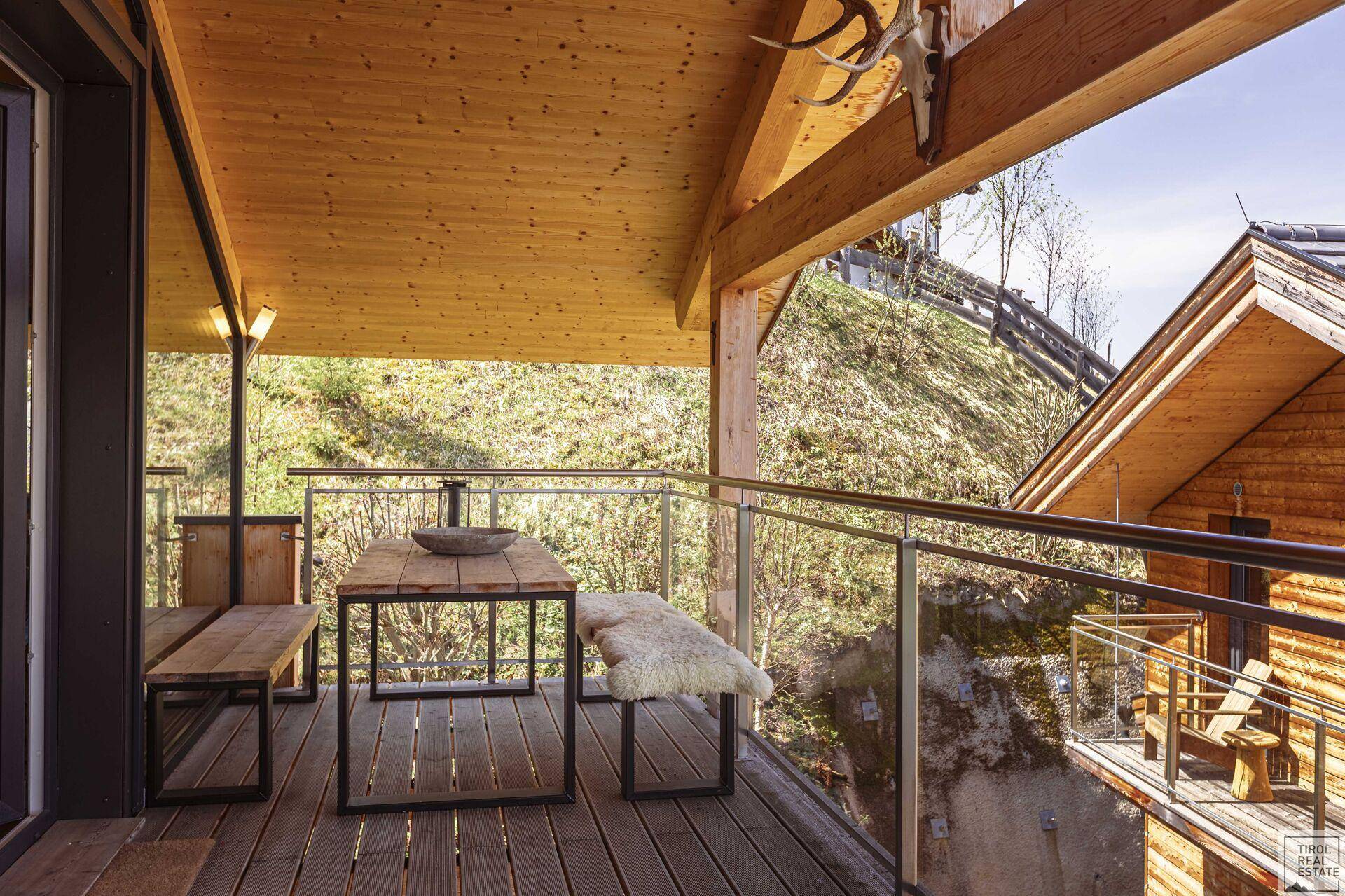Geräumiger Balkon mit Holzboden, Esstisch und Blick auf die Berge.