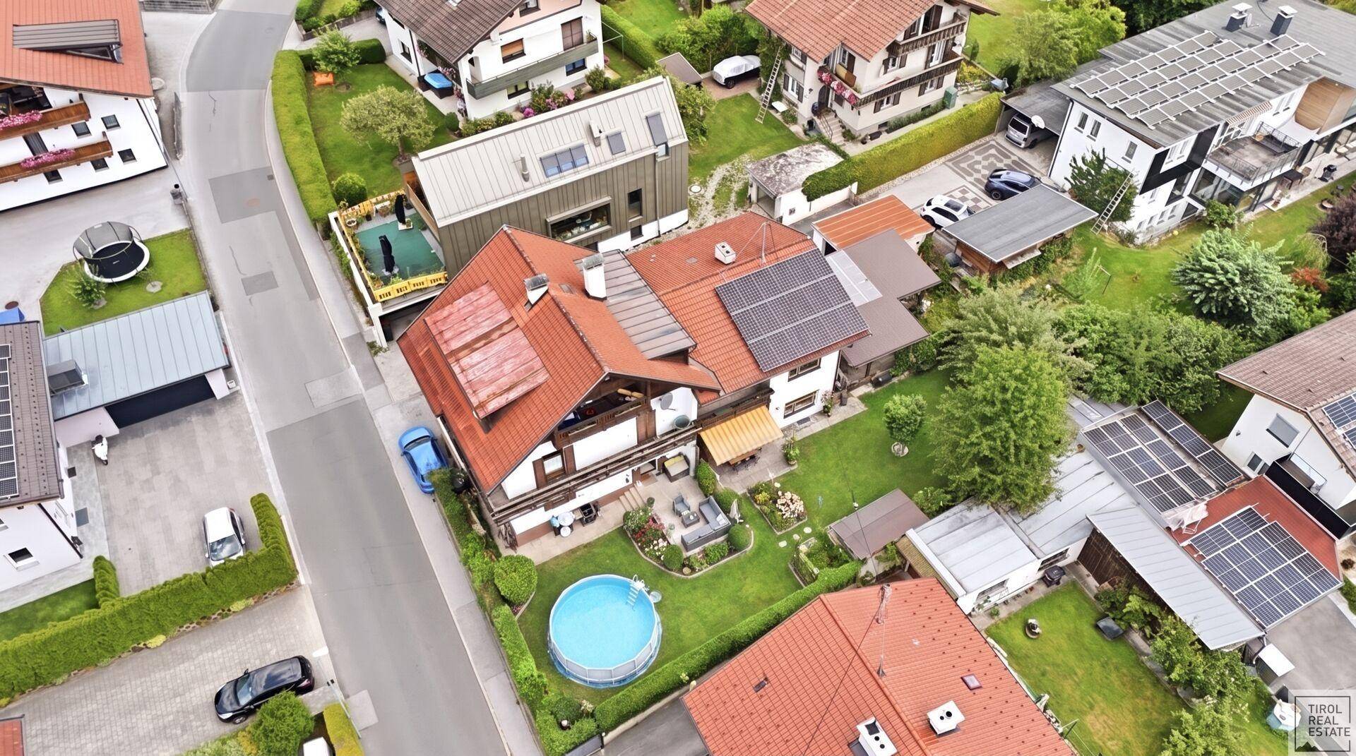 Luftaufnahme des Anwesens mit Solaranlagen auf dem Dach und einem Pool im Garten.