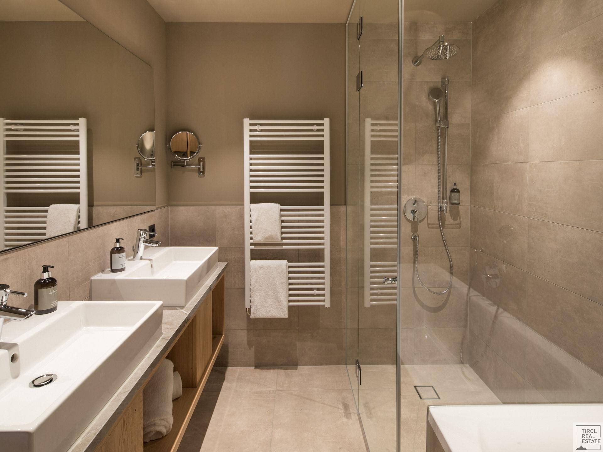 Modernes Badezimmer mit Doppelwaschbecken, großer Dusche und beheiztem Handtuchhalter.