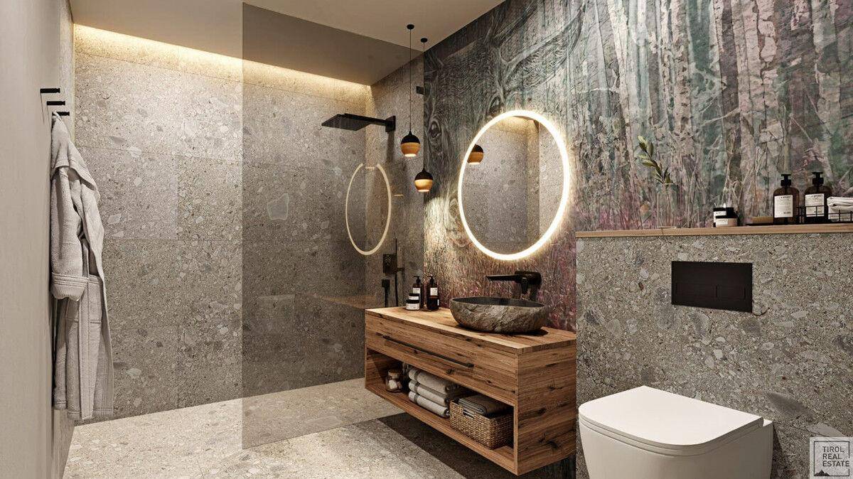 Modernes Badezimmer mit grauen Fliesen, Holzwaschtisch und runden beleuchteten Spiegeln.