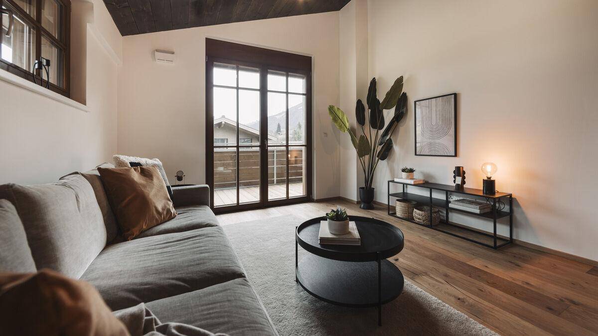 Gemütliches Wohnzimmer mit Sofa, Couchtisch und Zugang zu einem Balkon.