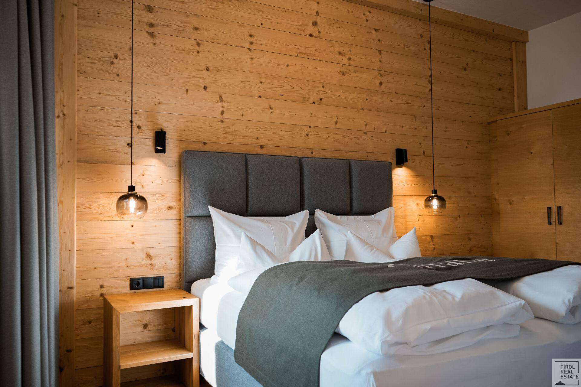 Helles Schlafzimmer mit Holzwänden, Doppelbett und praktischen Einbauschränken.