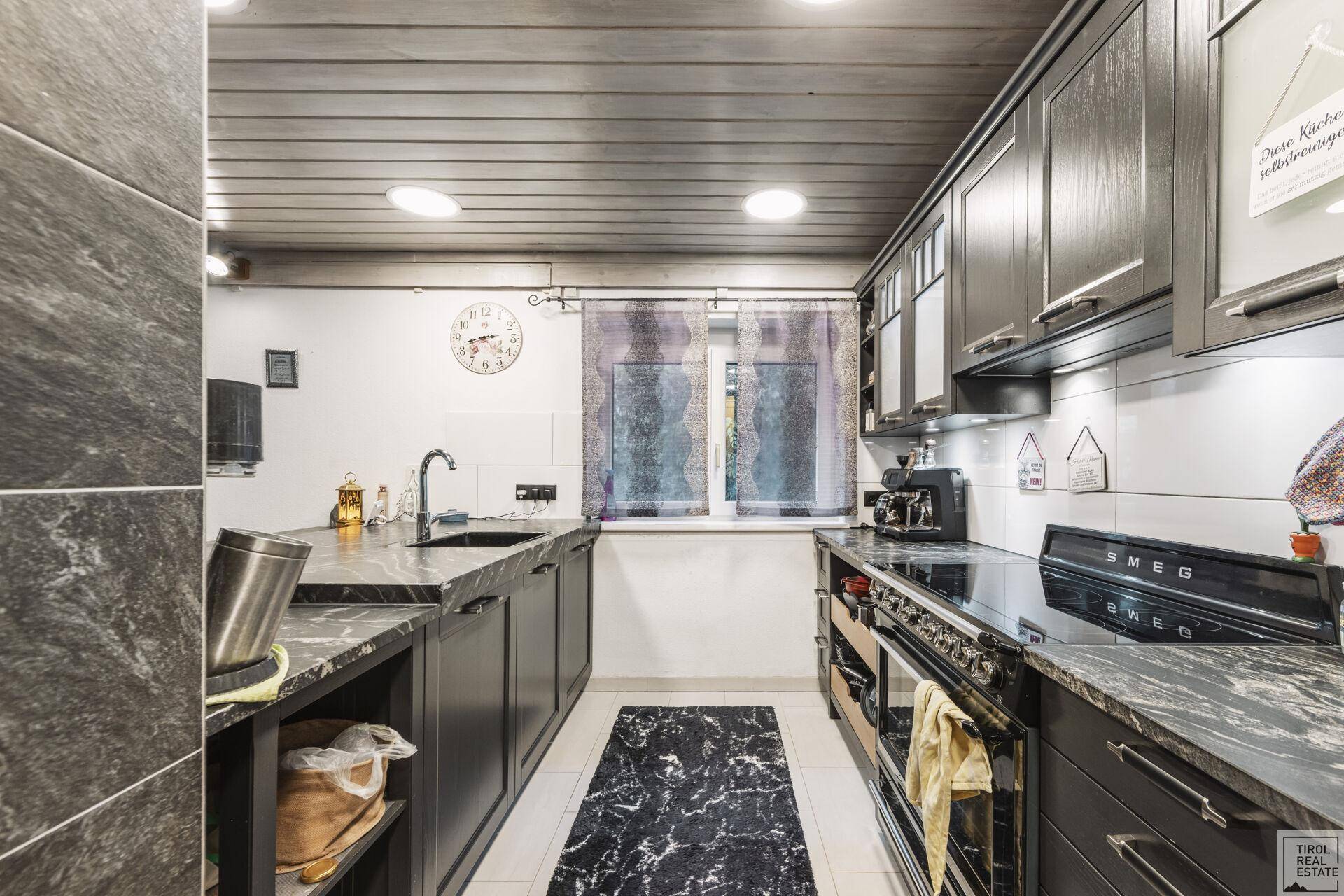 Moderne Küche mit dunklen Schränken, Granitarbeitsplatten und integrierten Geräten.